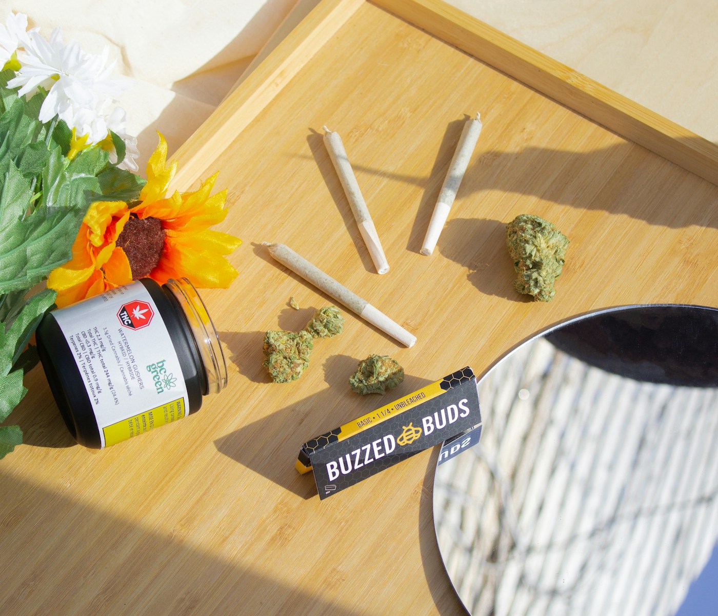 Cannabis flower, pre-rolls, and packaging arranged in sunlight